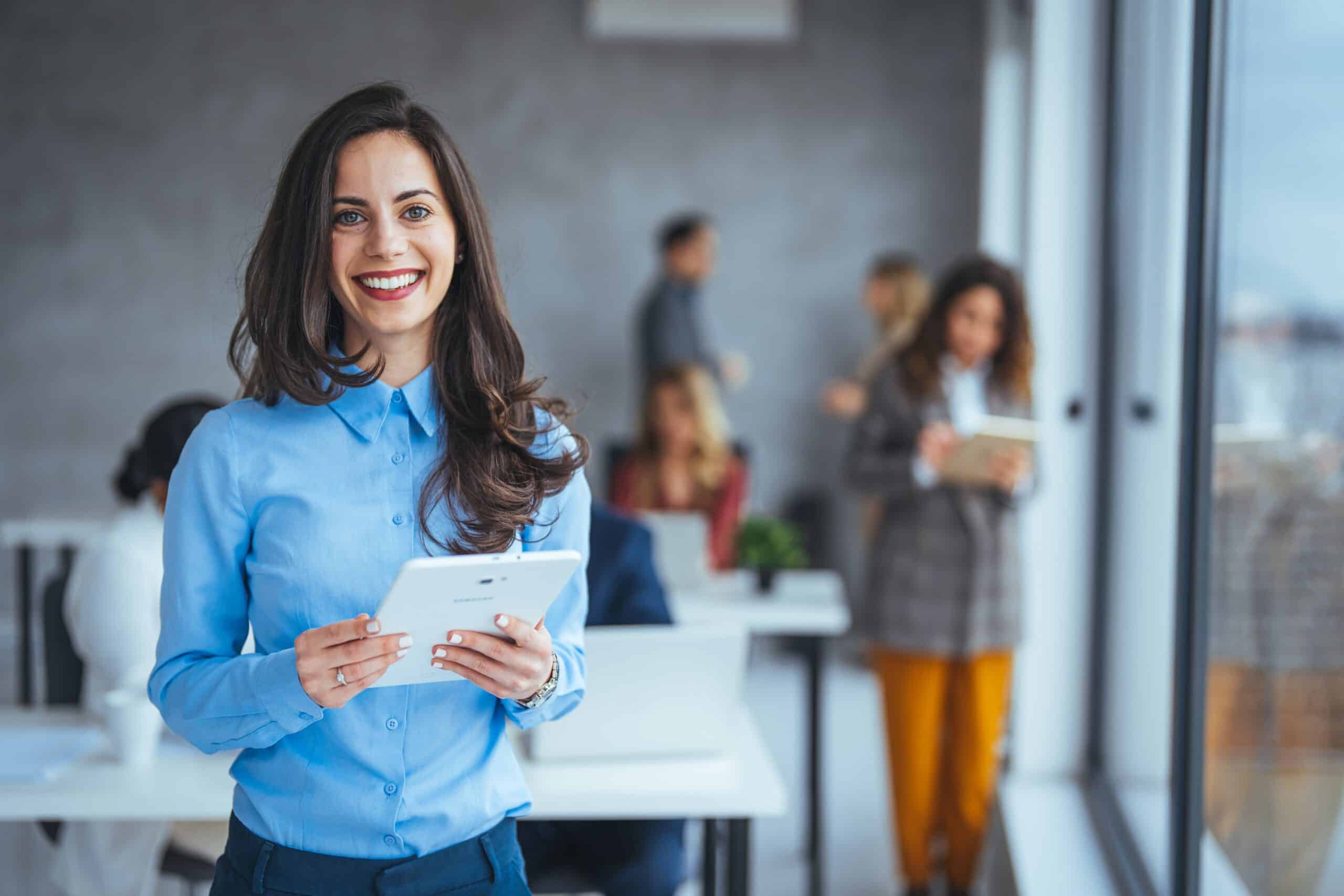Glad kvinnlig arbetsgivare håller i en ipad och ser glad ut efter att ha genomfört en lyckad vetting av personal och anställda
